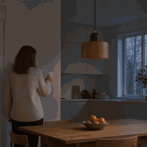 Woman switches on the Colora glass pendant light in the kitchen