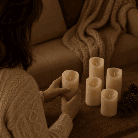 Woman places flameless LED pillar candles on the coffee table and they light up with a flickering flame