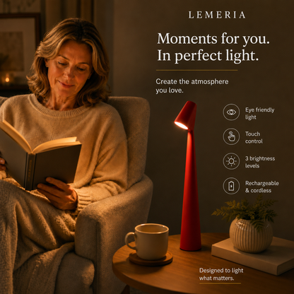 Woman reading in the armchair next to the red NordicEleganz cordless LED table lamp with touch control